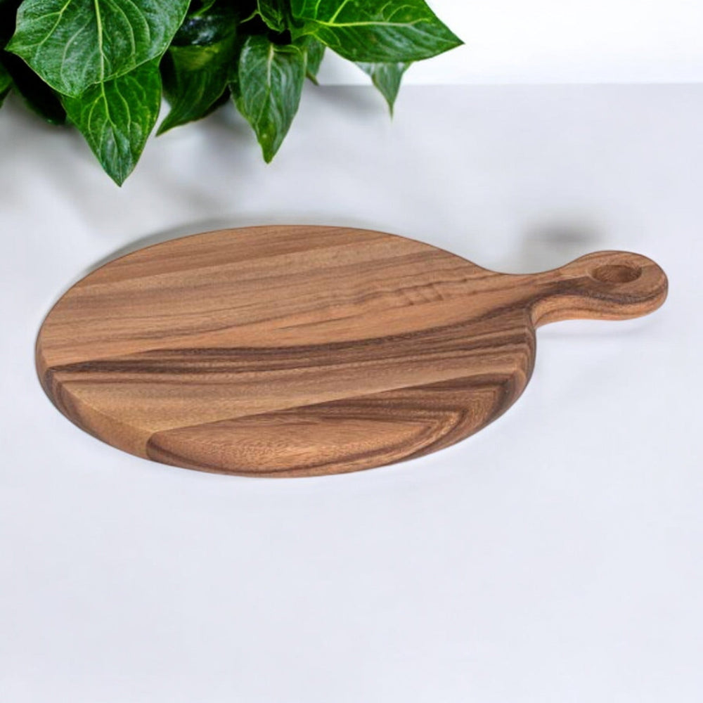 
                  
                    12" round acacia wood cutting board on white background with greey leaves
                  
                