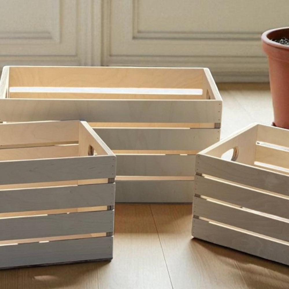 Set of wooden crates on a light wooden floor with a plant in the background.