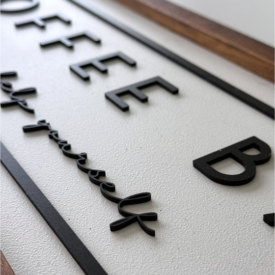 Close-up of a sign with 'Coffee Bar' text on a textured surface.