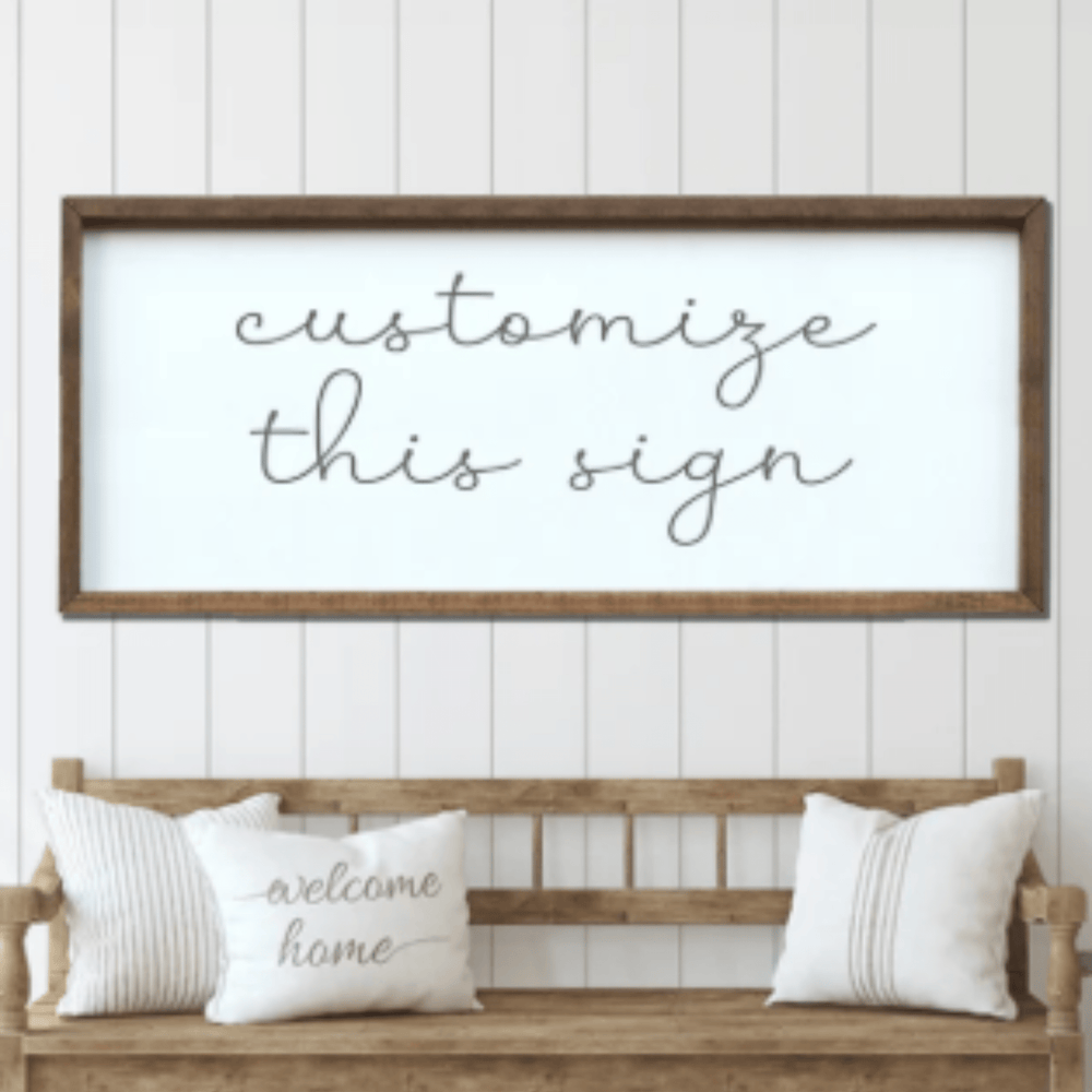 Wooden bench with pillows and a framed sign on a white paneled wall.