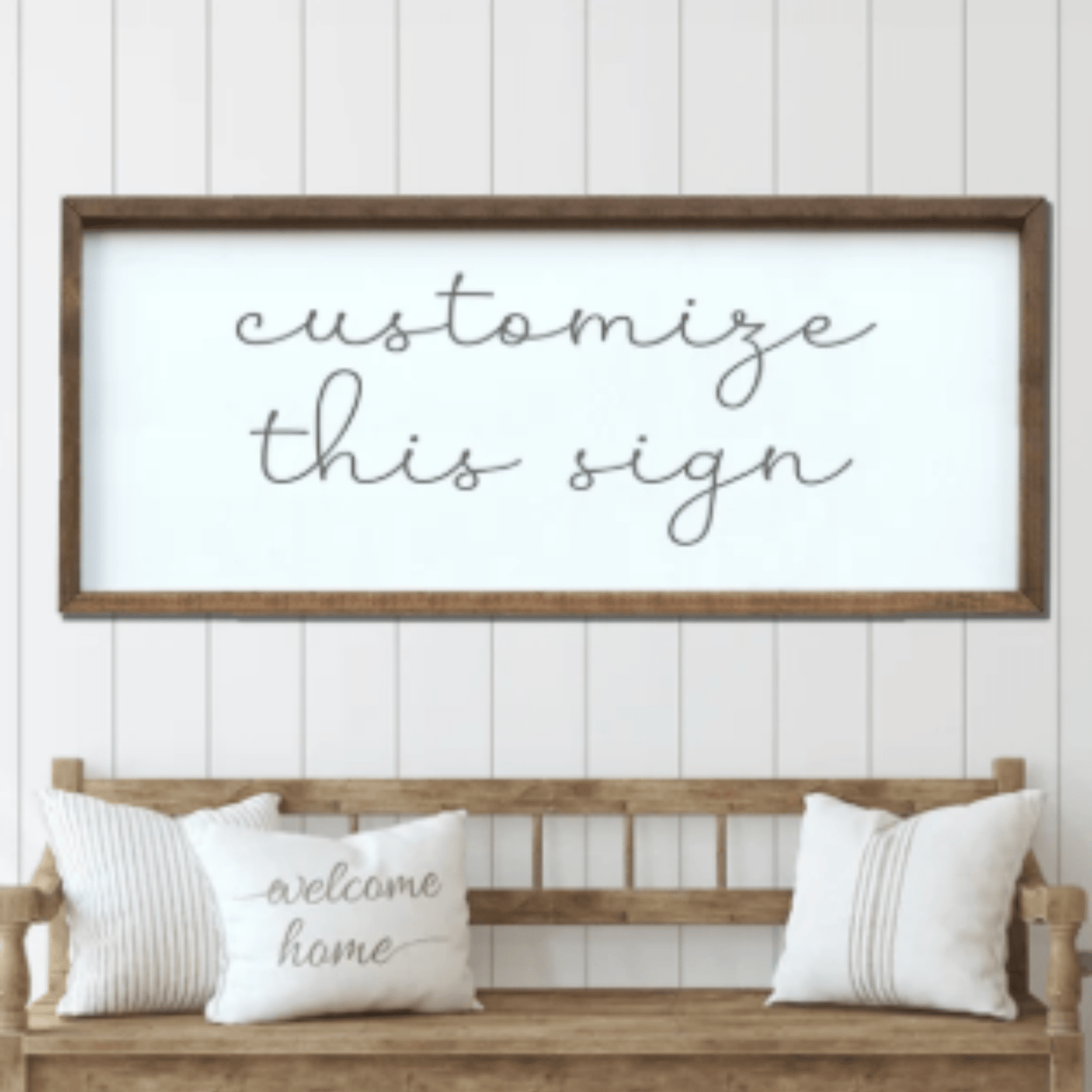 Wooden bench with pillows and a framed sign on a white paneled wall.