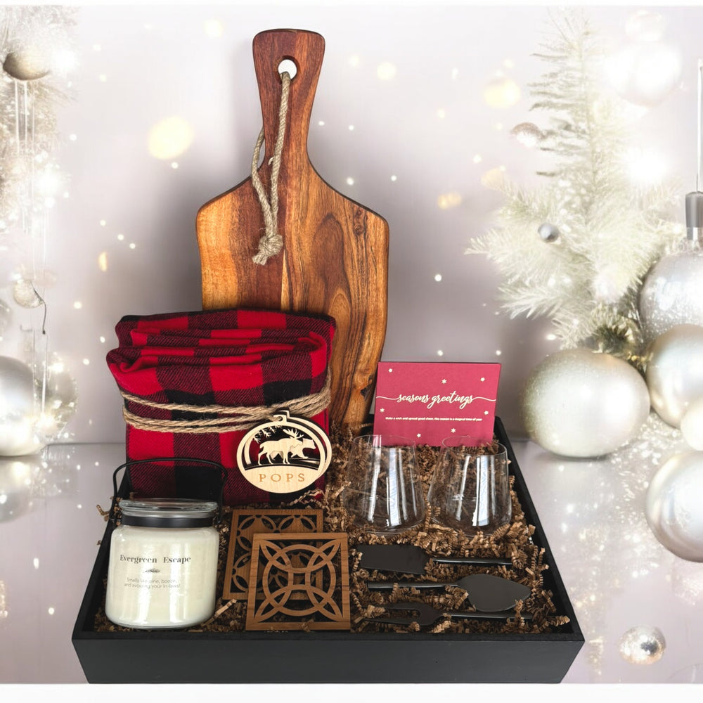 Gift set with wooden cutting board, plaid towel, candles, and decorative items on a festive background.