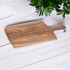  acaica board with handle and leather string on white washed table twith green plant at the side