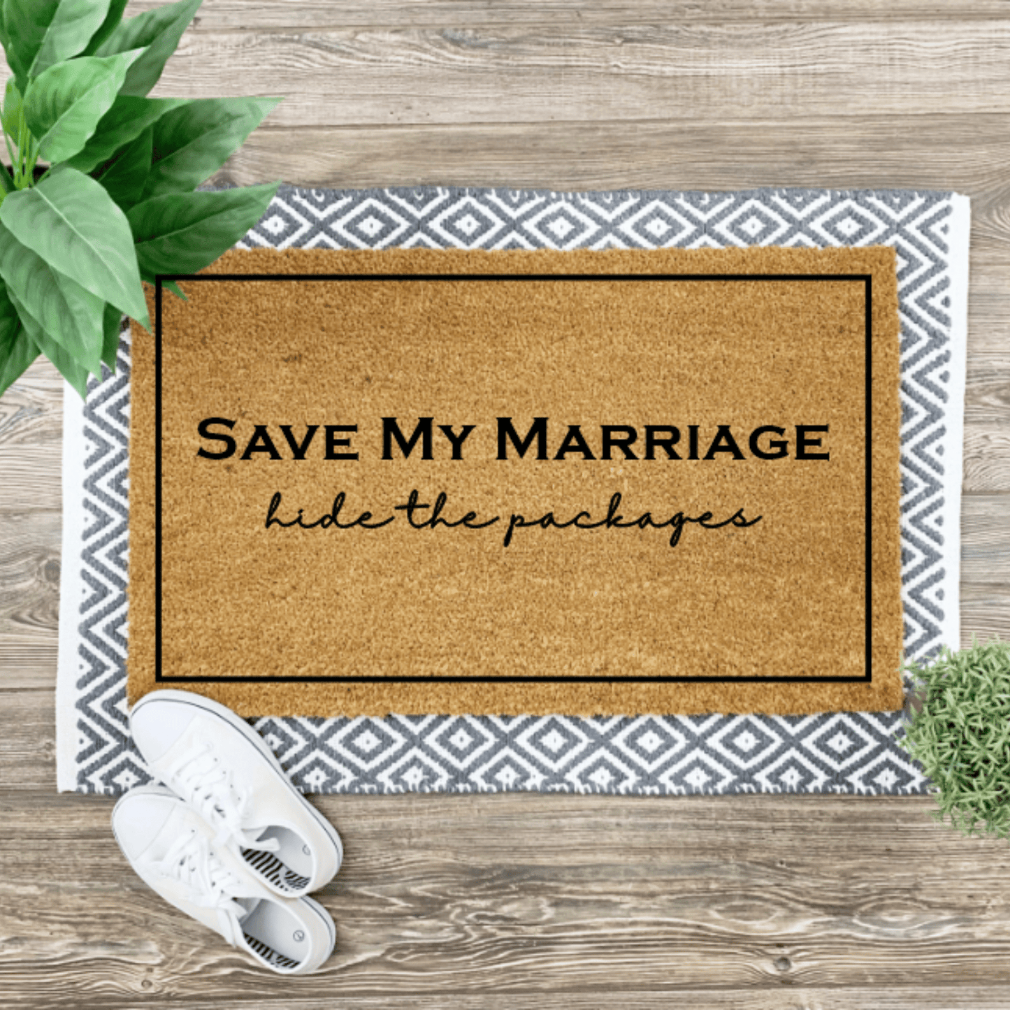 coir mat that says save my marriage hide the packages in black with a border.  coir mat sitting on woven grey and white mat with white sneakers and placnt on side of mats.
