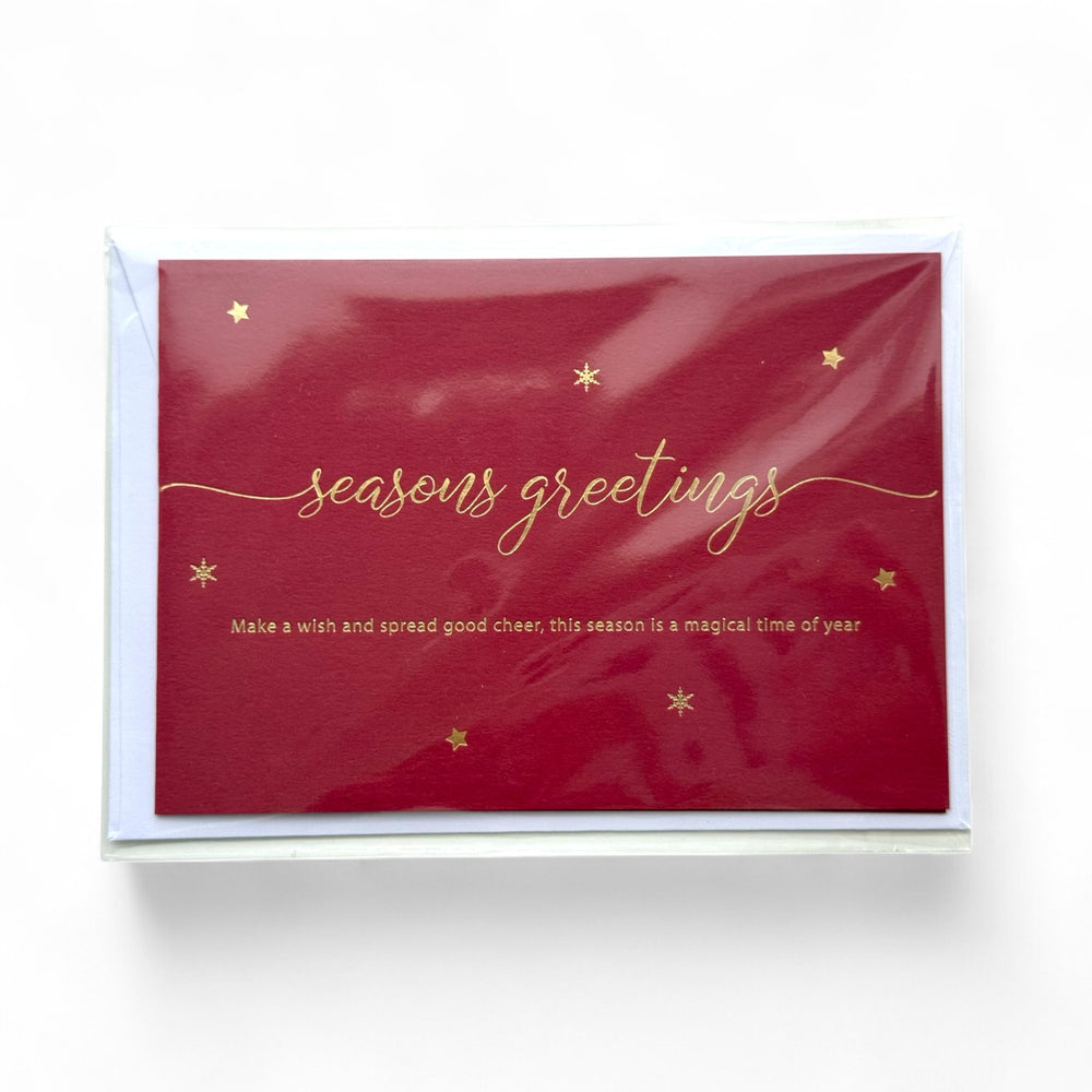 
                  
                    Red greeting card with gold embossed 'seasons greetings' text and stars on a white background
                  
                