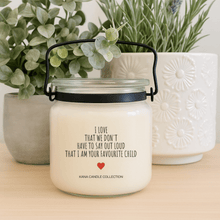  Mother’s Day soy candle with label that reads “I Love That We Don’t Have to Say Out Loud That I Am Your Favourite Child” on a wood table with small planters and greenery