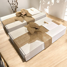  White gift boxes with burlap ribbons on a wooden surface