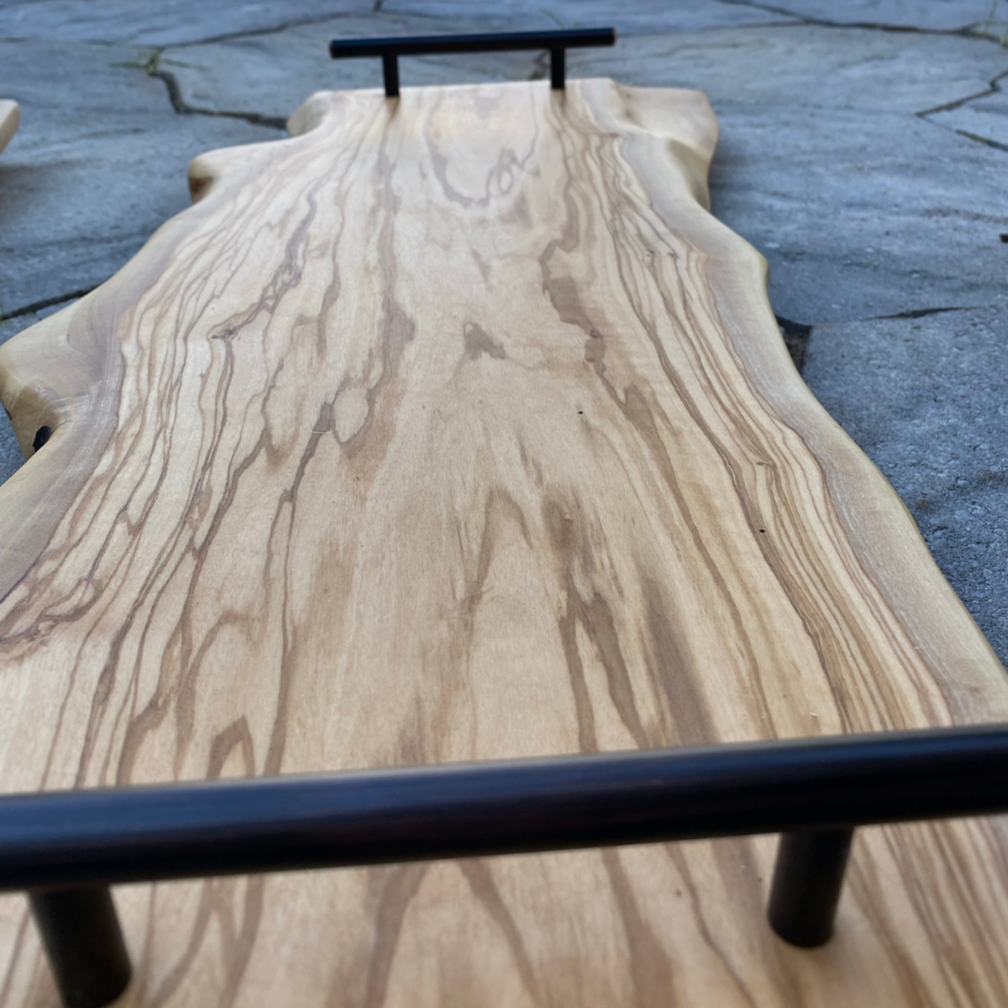 closeup of 24-inch live edge olivewood charcuterie board with black handles