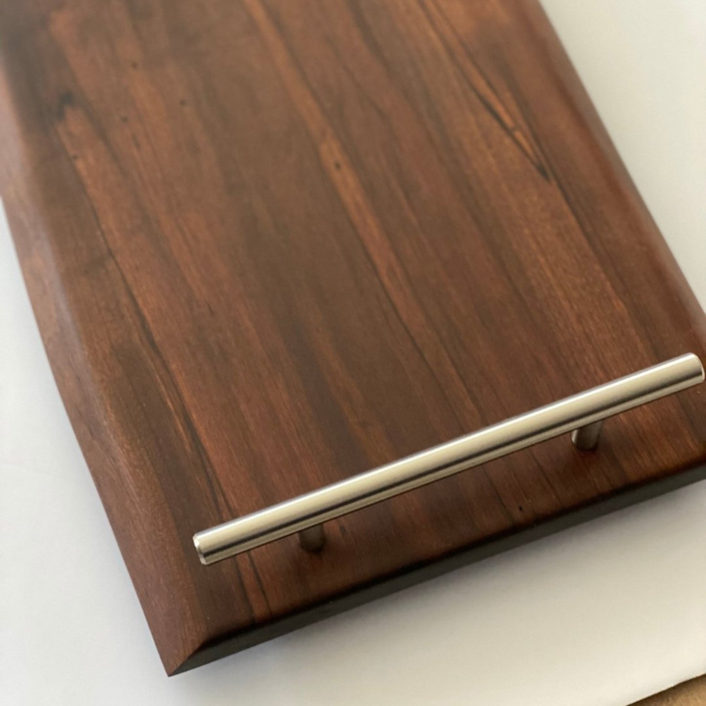 closeup of 24-inch live edge roasted maple charcuterie board with rich grain, custom silver handles, 