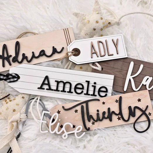 
                  
                    Various Wood Gifts tags in different shapes sizes and colour with laser cut names adhered to the front
                  
                