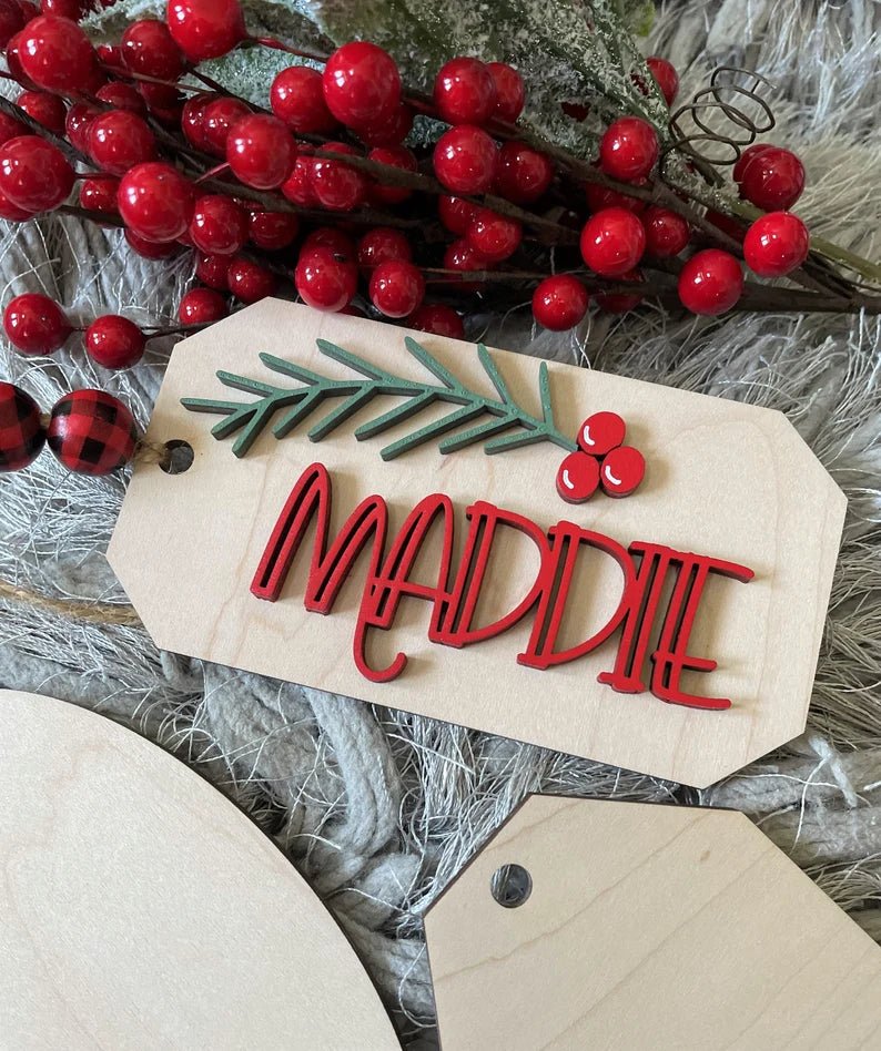 
                  
                    Wooden Christmas Baltic Birch gift tag with Red name and green holly cut out adhered to the front
                  
                